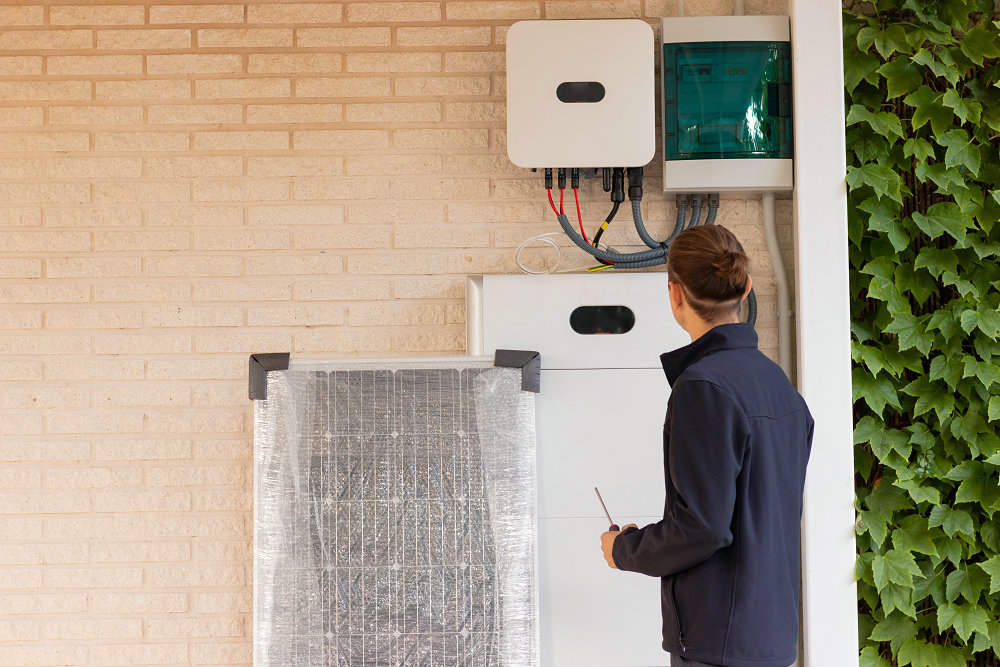 Vista trasera de un joven técnico irreconocible instalando un sistema solar para energía renovable