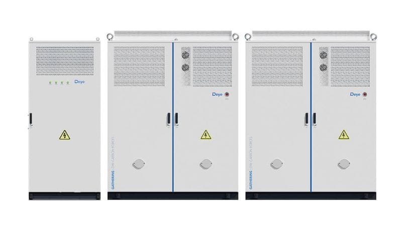 Three industrial electrical cabinets with vents, warning signs, lights, and handles stand side by side against a white background.