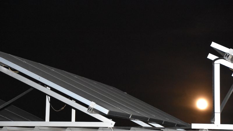 - Solar panels installed at night with the moon in the background, showcasing renewable energy solutions.