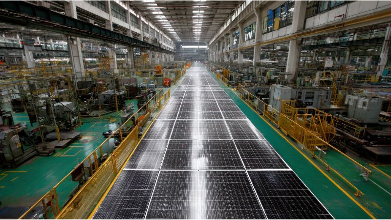 Solar panel manufacturing facility with large solar panels being produced and assembled.